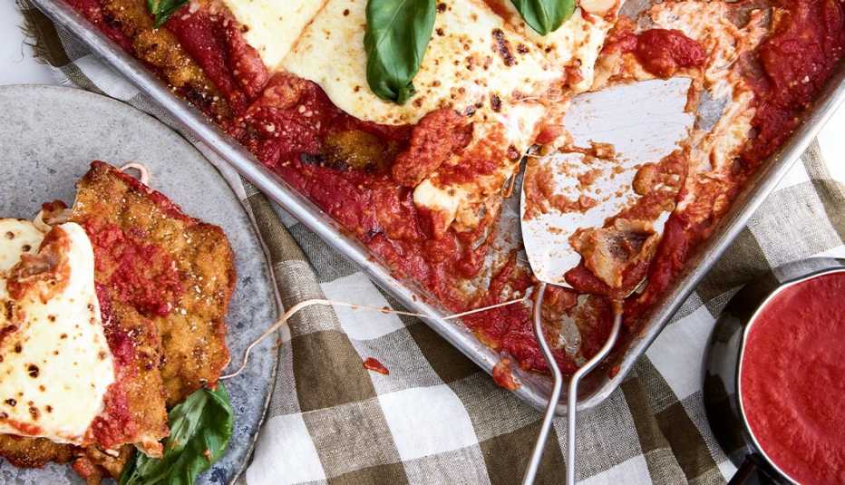 Chicken parm in pan, with piece on plate next to it