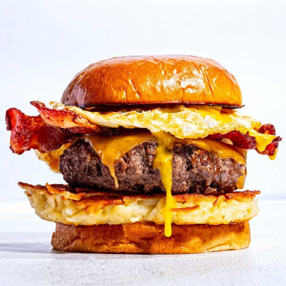 A breakfast burger with potato, a burger patty, bacon and egg