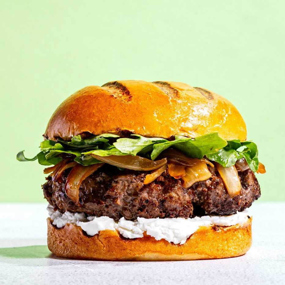 A hamburger with goat cheese, caramelized onions and greens
