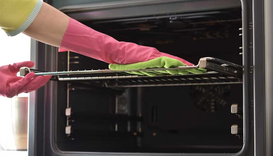 Woman's hand in household cleaning gloves cleans oven 