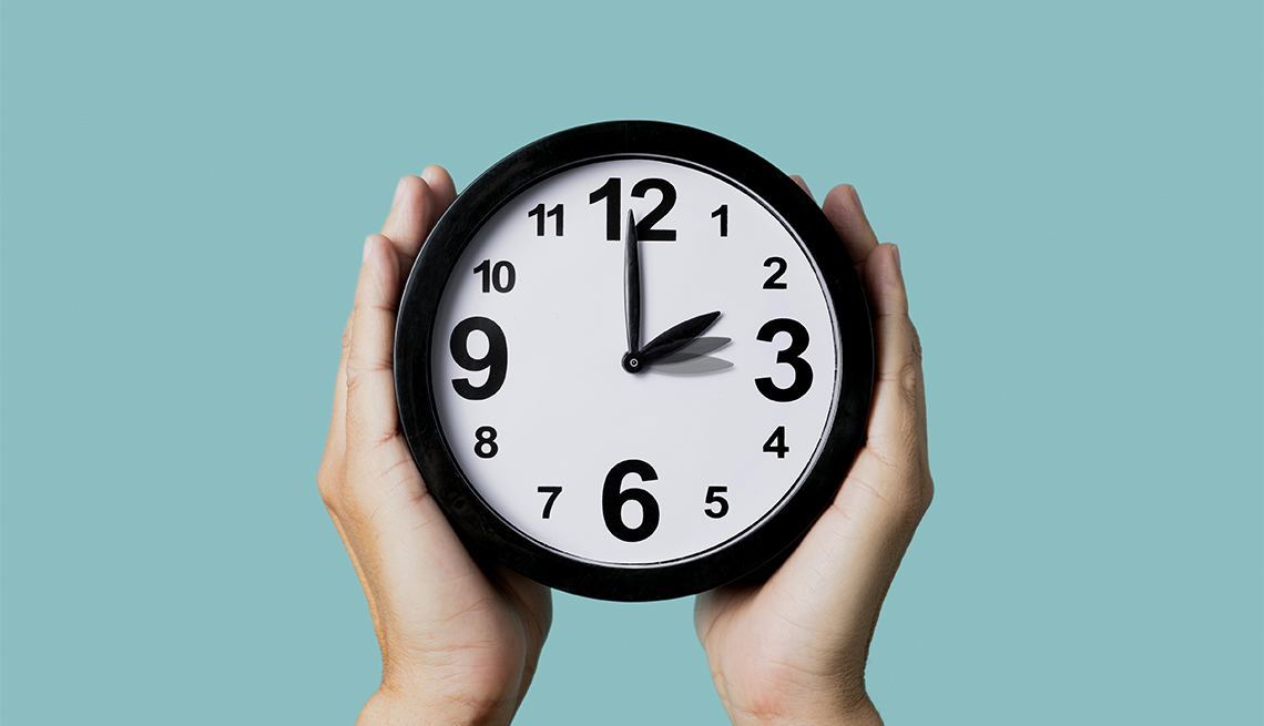 closeup of the hands of holding a clock changing at the beginning daylight saving time