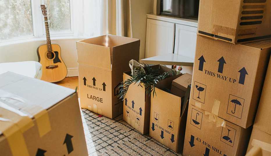 A sunny living room with many cardboard boxes, filled with possessions