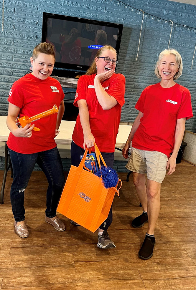 Workshop coordinators Taylor Blomquist, JC Ward and Carol Mahoney display a giveaway caulk gun and tote bag of DIY home repair tools.  