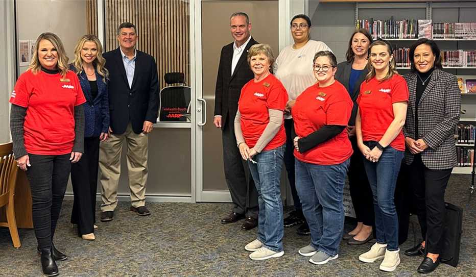 AARP Oklahoma and library staff and volunteers stand in front of the telehealth booth