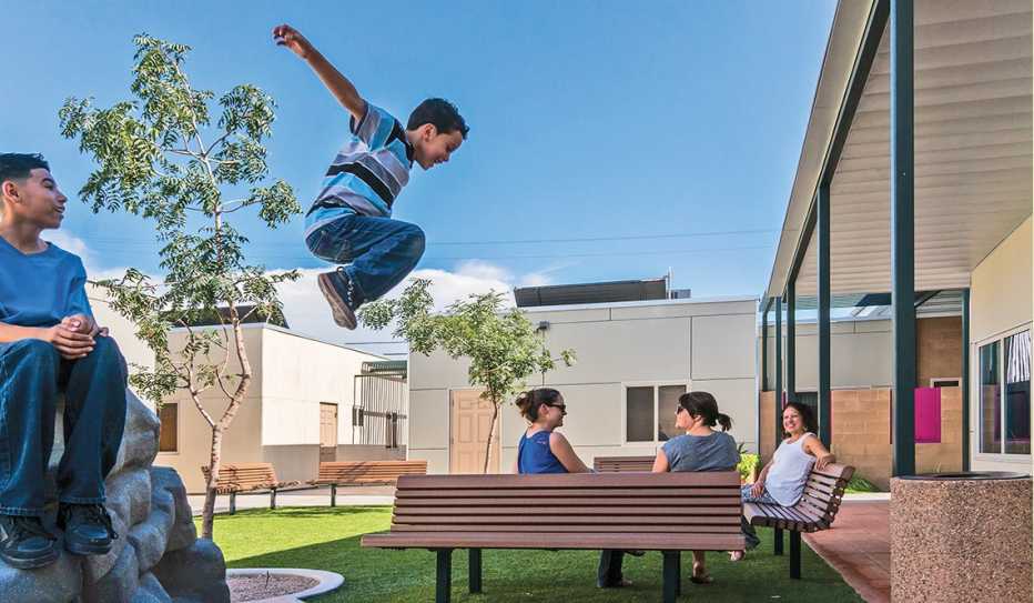 Three women and two young boys gather in the courtyard of the Las Abulelitas Family Housing community