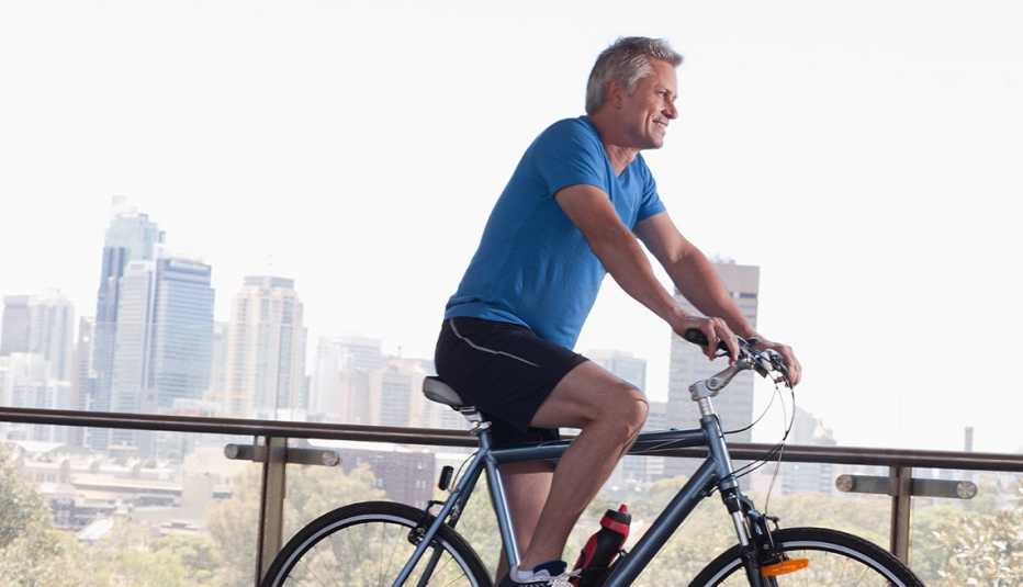 A mature man riding a bicycle near a city. Unlike a generation or so ago, bicycles are now used by people of all ages.