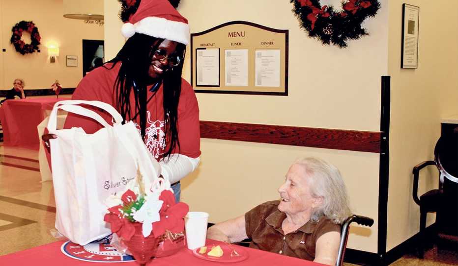 A Silver Stars volunteer delivers holiday gifts to a woman in a nursing home