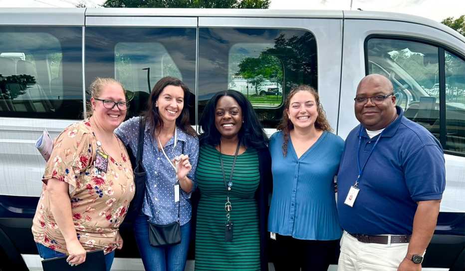 Representatives from Mecklenberg, North Carolina's on-call transportation service stand in front of a shuttle bus