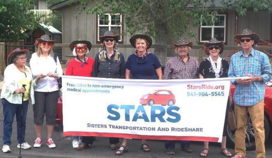 Volunteers with the STARS transportation service display a parade banner