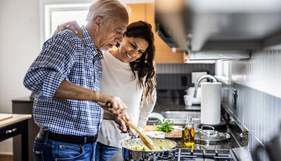 Mature man and his adult daughter preparing a healthy meal together in the kitchen