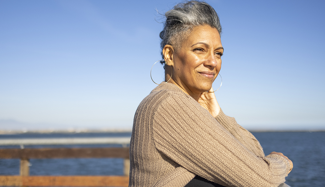 a woman is standing on a pier at the beach