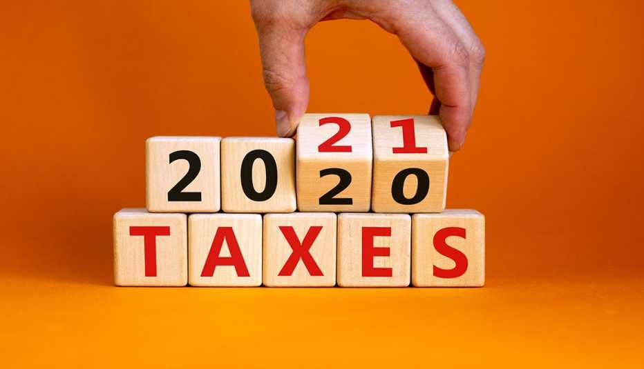 a hand reaching into the top of the photo is  flipping wooden cubes that spell out 'Taxes 2020' to 'Taxes 2021' 