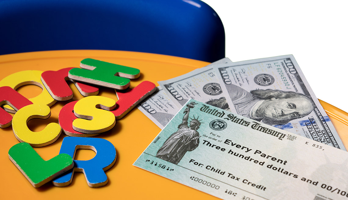 US Treasury illustrative check for child tax credit on table with 3 hundred dollar bills and colorful letters