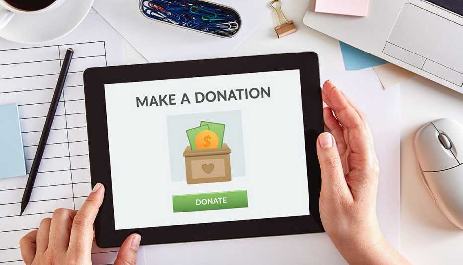 Hands using a digital tablet to donate money to charity