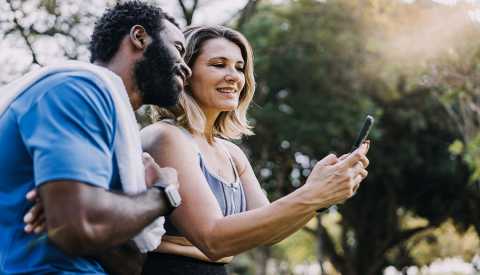 Couple taking a break from exercising to look at their smartphone