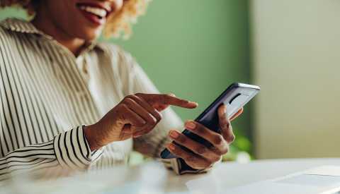 woman typing text message on her smartphone while sitting at office desk