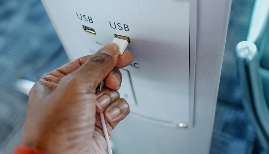 A man plugging a charger into a USB port in a public place