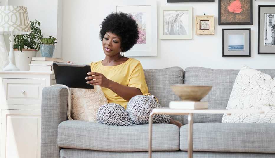 Woman using digital tablet on sofa