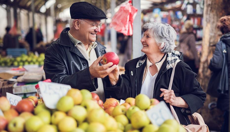 Smiling senior couple buying fruit together at farmer's market.
