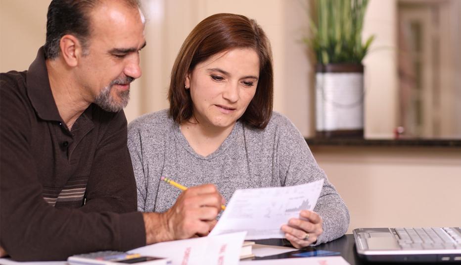 Mature couple working on family finances at home together. They pay bills, complete income taxes, apply for home loan, investing, or pay off a credit card.