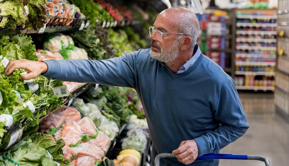 The mature man is able to find his selection on the well stocked produce shelves in his local grocery store.