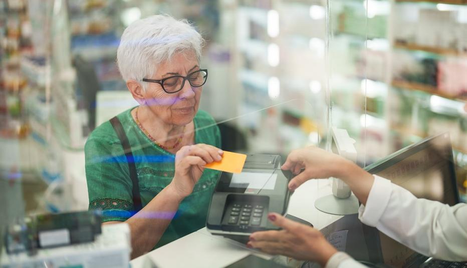 Senior woman paying for medicines at pharmacy checkout