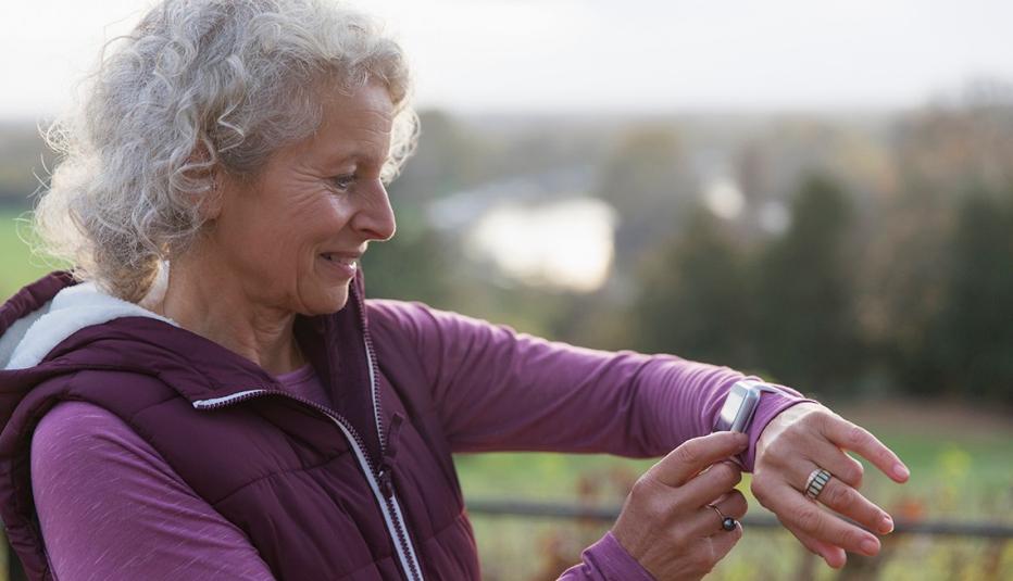 Active senior woman exercising, using fitness tracker smart watch