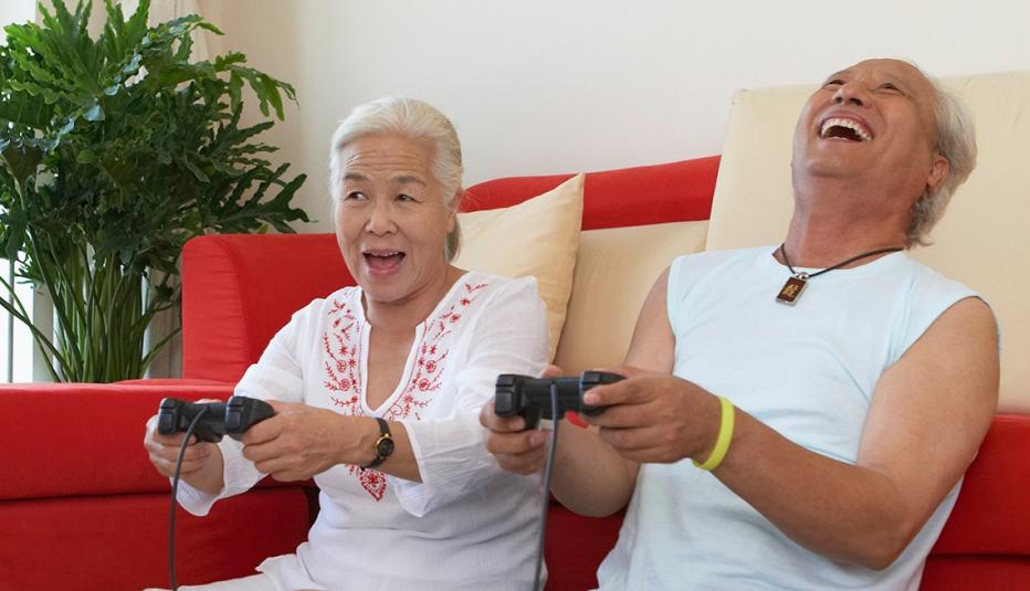 Couple sits on the floor, each holding a video game controller and laughing