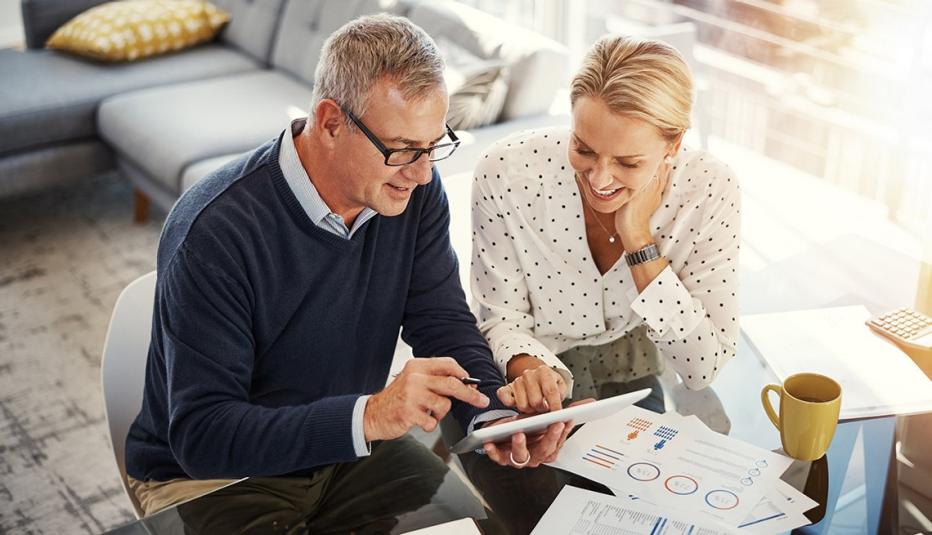 Couple using a digital tablet while going through financial paperwork