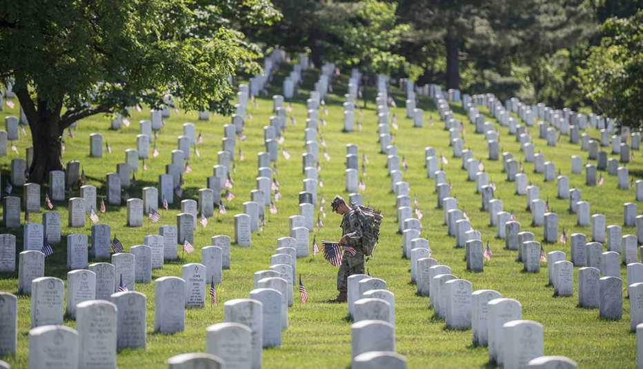A soldier places flags at a cemetery