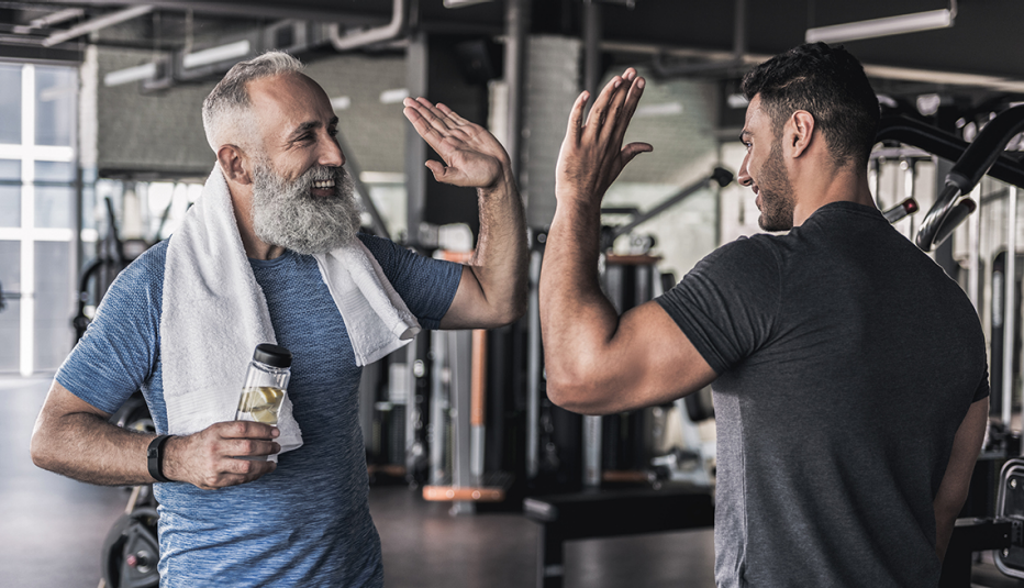 Two friends high five while working out in a gym