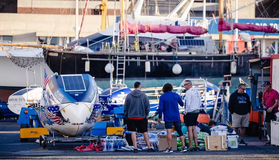 members of the foar from home rowing team stand on the dock next to their boat