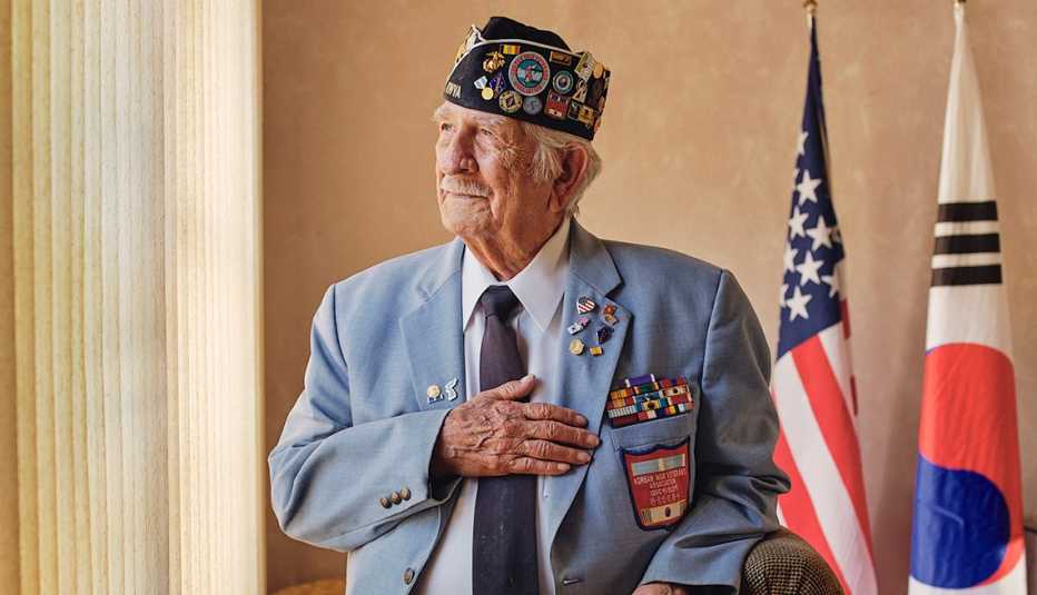 Sal Scarlato places his hand on his chest. American and Korean flags are in the background.