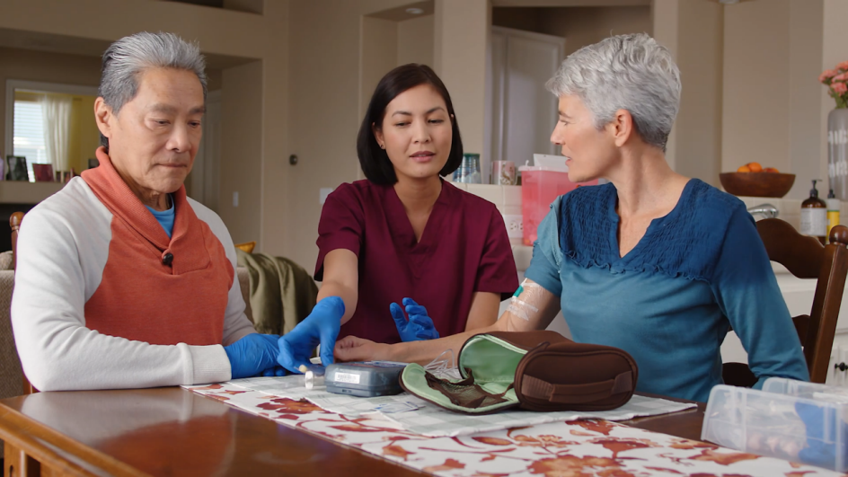 man and woman with nurse showing them how to use medicine at home
