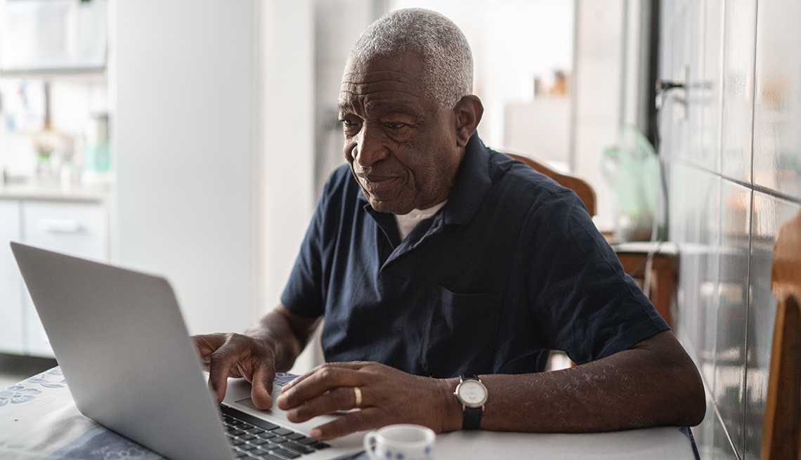 A man is working on his laptop at a table in his home
