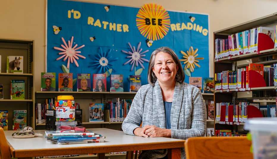 ingrid fournier sits at a desk smiling in a library