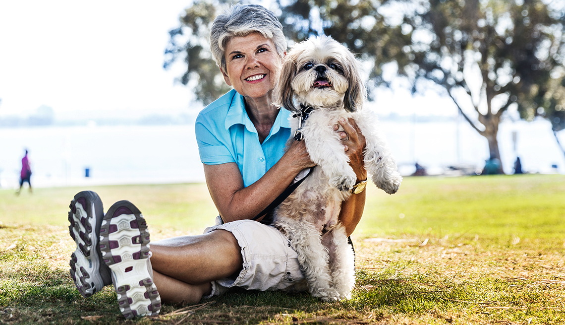 Dog walker Sari Reis sitting in the park, holding a small dog