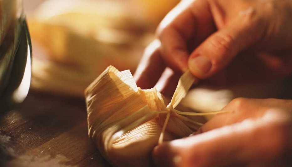 Manos de una persona envuelven un tamal