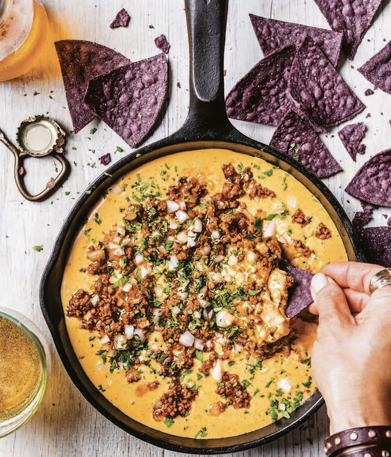 Sartén con queso fundido cubierto con chorizo, cebollas y chiles