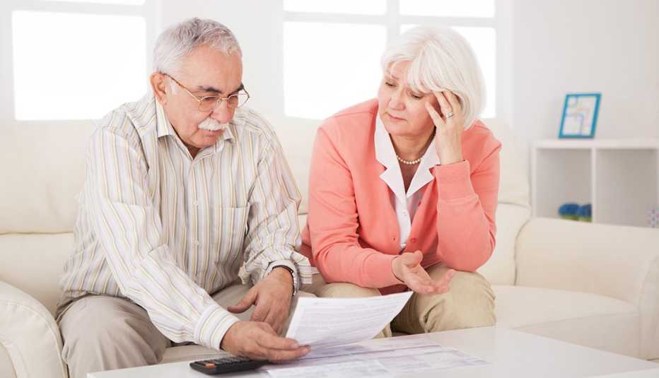 Pareja mayor en una sala viendo unos papeles.