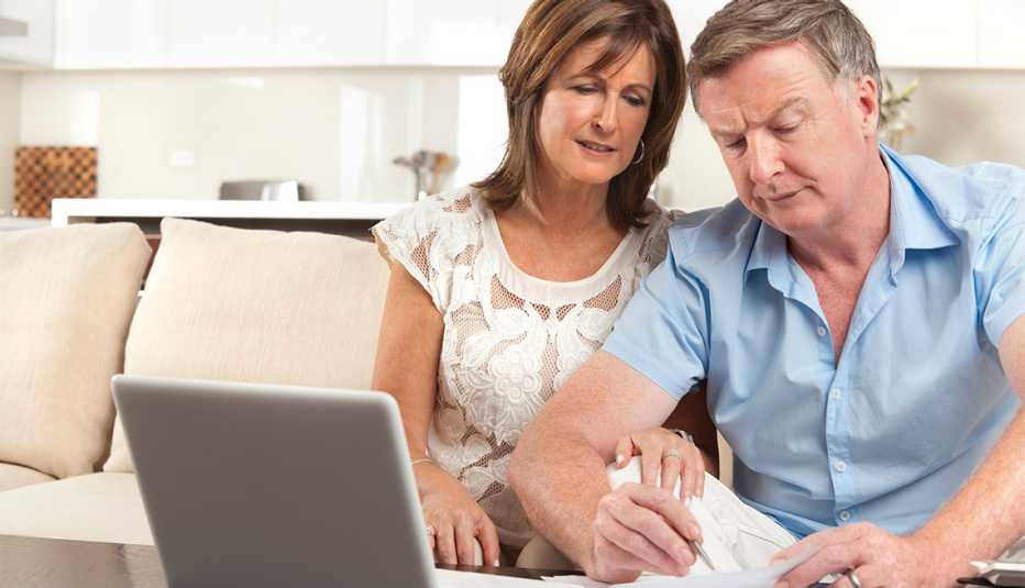 Pareja mirando cuentas en la sala de su casa y frente a la computadora.