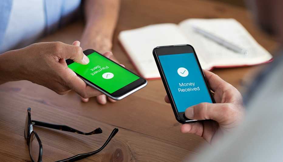 Un hombre y una mujer sostienen sus teléfonos inteligentes mientras hacen una transacción de pago electrónico