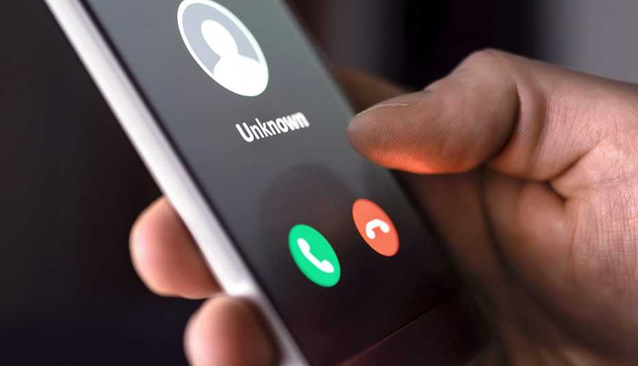 Persona sostiene un teléfono inteligente con un número desconocido en la pantalla.