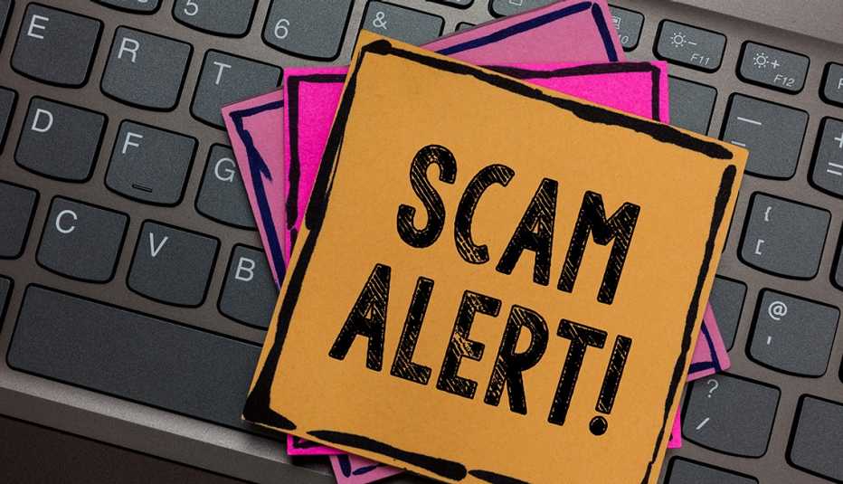 Teclado de un computador con una nota encima que dice alerta de fraude