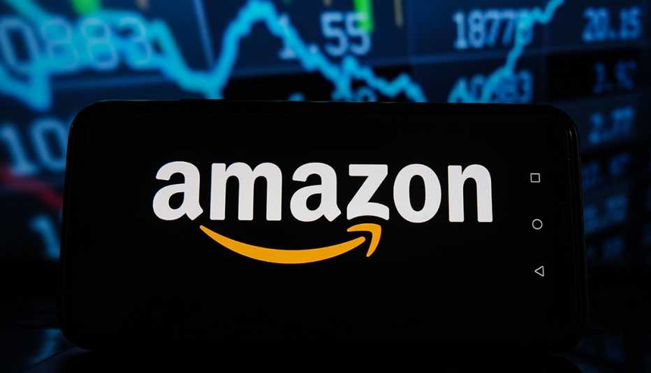 Logo de Amazon que se ve en la pantalla de un teléfono y delante de una gráfica estadística de inversiones.