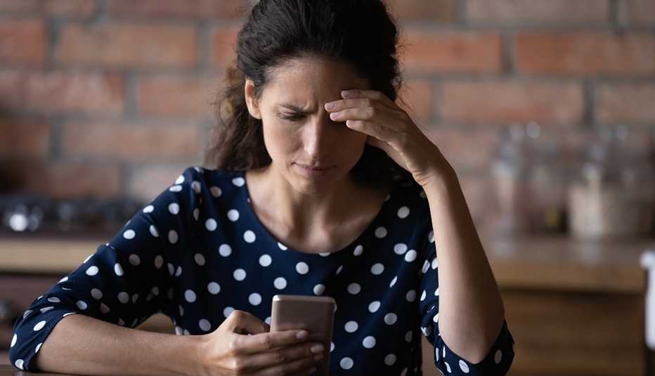 Mujer viendo su teléfono móvil y con cara de preocupación