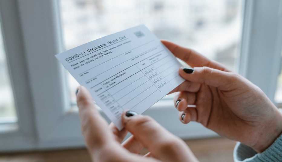 Manos sostienen una tarjeta de vacunación contra la Covid-19