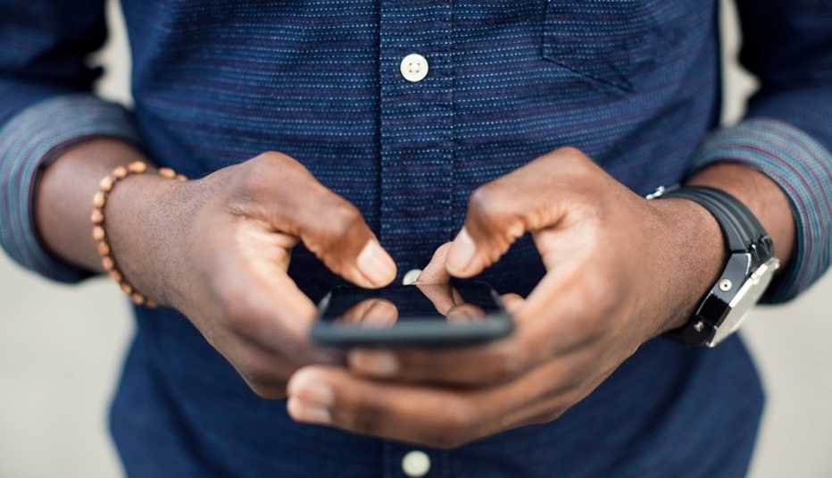 Manos de un hombre sosteniendo un teléfono móvil en sus manos