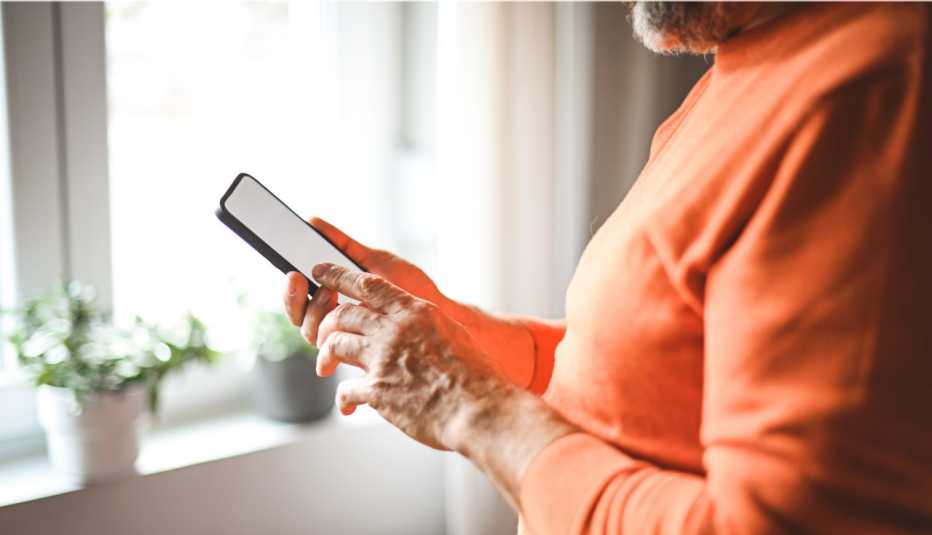 Persona mayor chequea un mensaje de texto en su teléfono móvil.