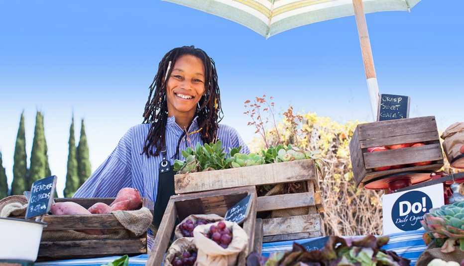 Mujer vendiendo vegetales orgánicos en una feria de mercado.